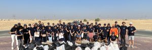 Group of individuals stands with collection of garbages after desert cleaning