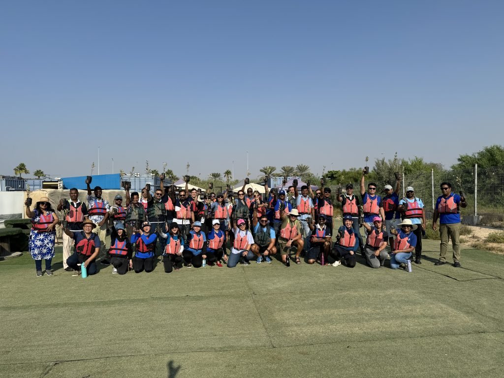 Group of people wearing safety vests standing outdoors for a group photo.