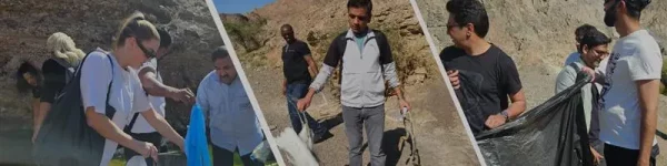 A group of individuals participates in an outdoor clean-up, collecting waste and engaging with the environment in a sunny location.