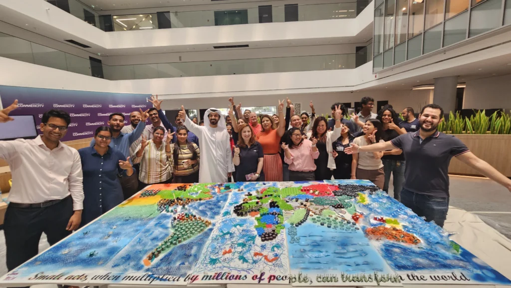 A diverse group of people celebrates around a colorful cake shaped like a world map, showcasing vibrant designs and messages of unity.