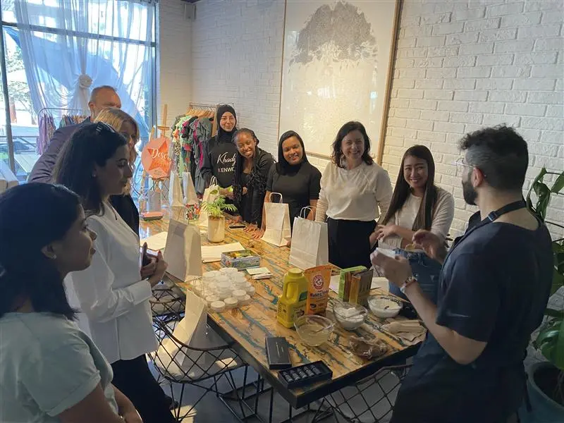 A group of people gathered around a table filled with gift bags, colorful crafts, and snacks, engaging in conversation and activity.