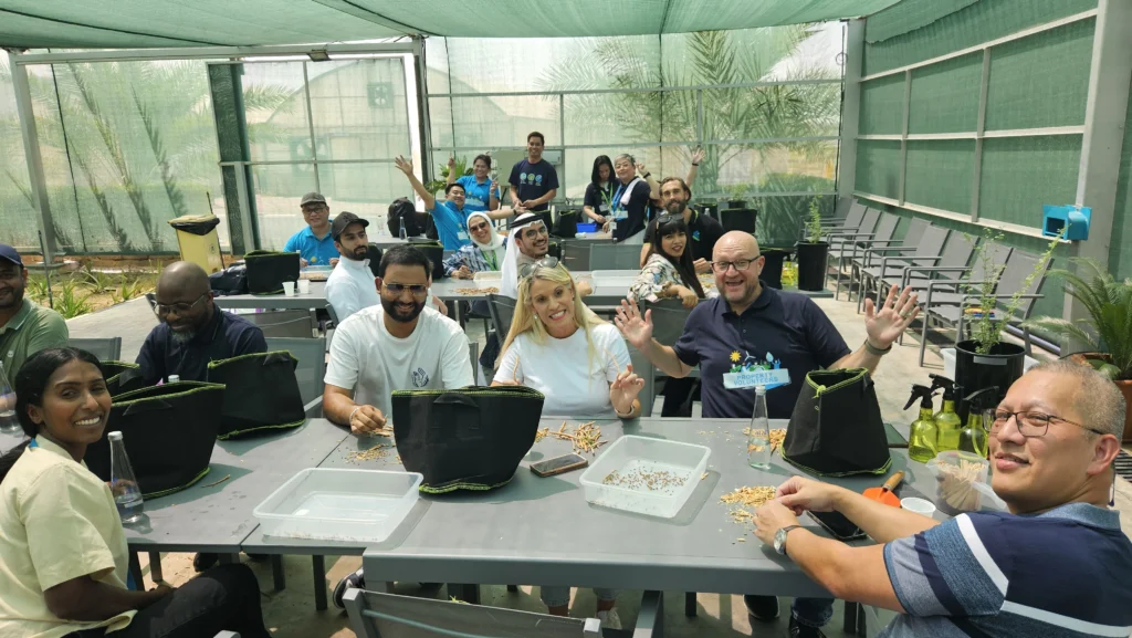 Group of people smiling and participating in a planting activity at an indoor garden workshop