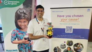 A person holds a colorful handmade toy next to a banner promoting community causes and social responsibility initiatives.