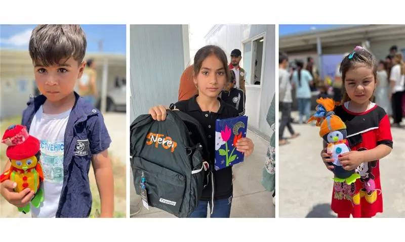 Three smiling kids with backpacks & toys outdoors