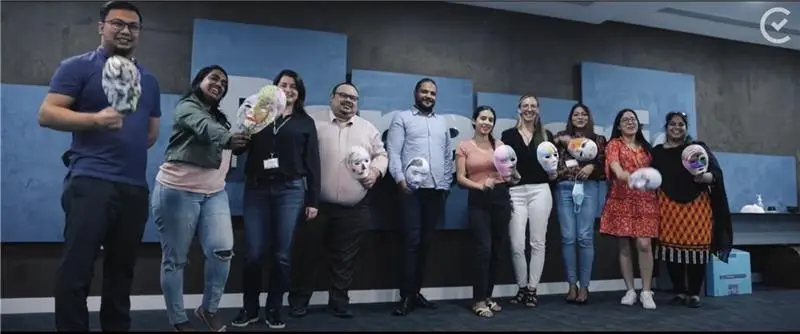 Smiling group holding decorated masks at team event