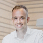 Smiling man in white shirt, wooden room background